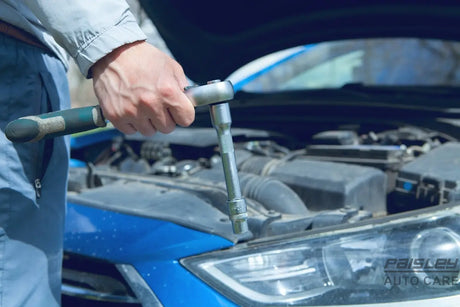 Mechanic using a wrench on a car engine.