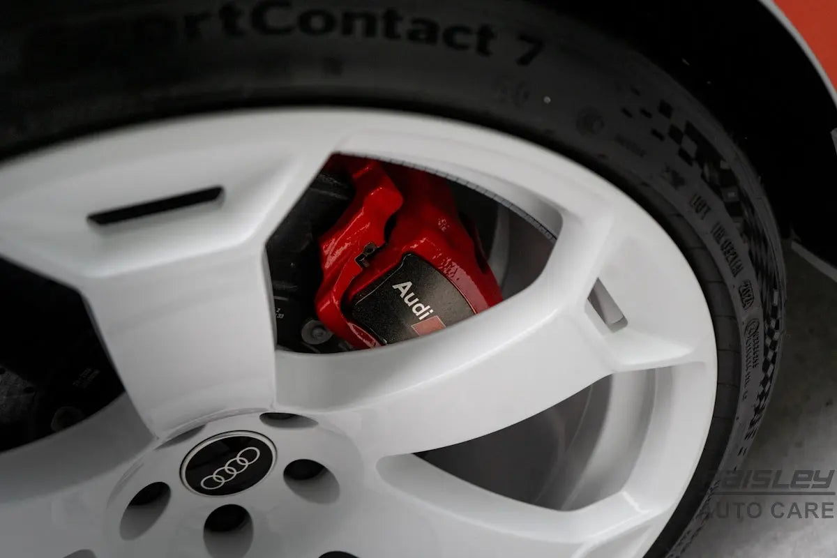 An audi wheel with a red brake caliper.
